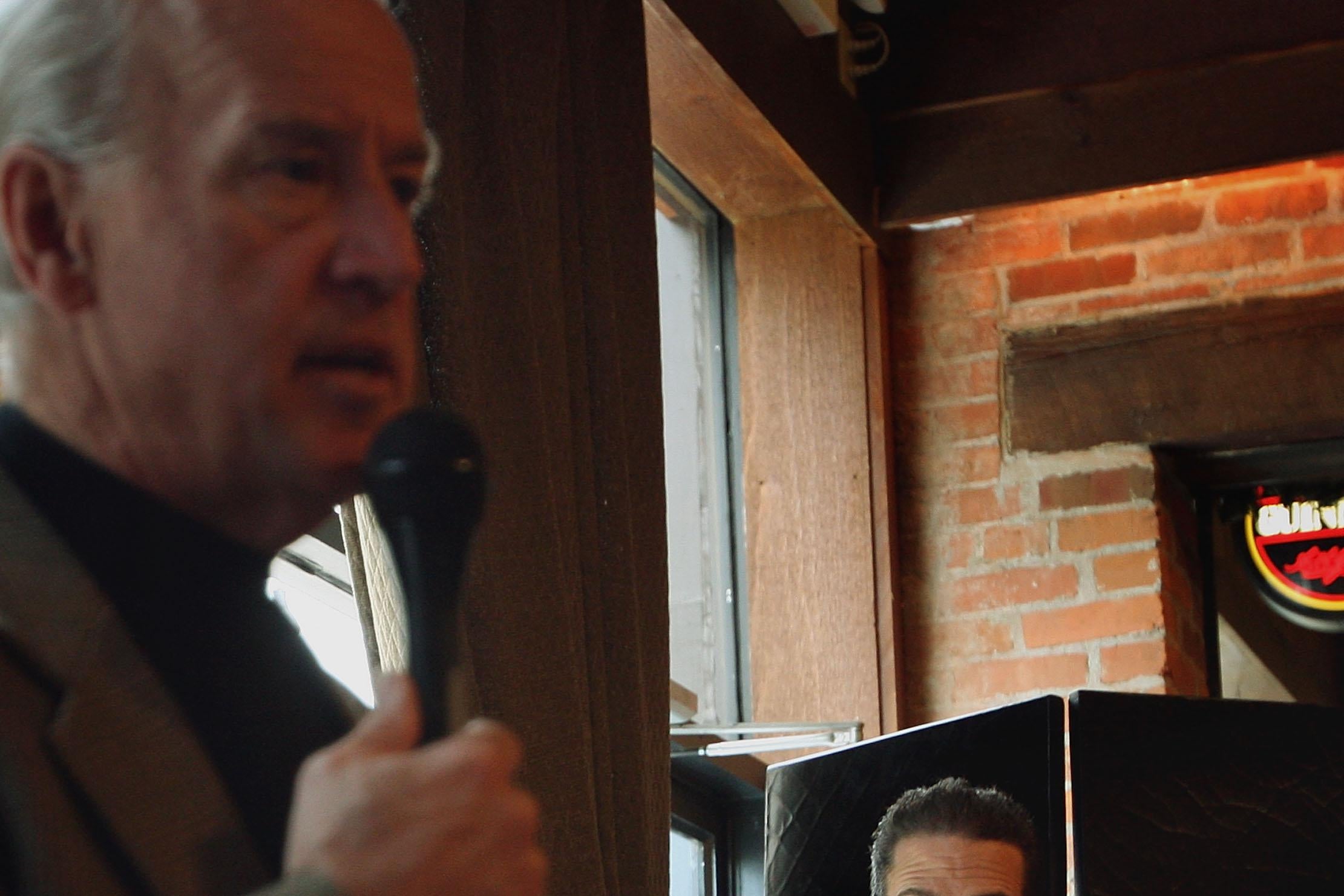 Hunter Biden stands in the background as Joe Biden holds a microphone
