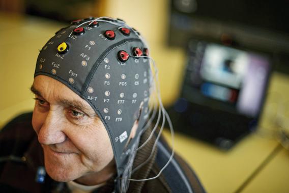 Patient Marc Andre Duc wears a cap with electrods next to a computer during a presentation of brain-machine interface by the Swiss Federal Institutes of Technology of Lausanne  on January 23, 2013 in Sion. 