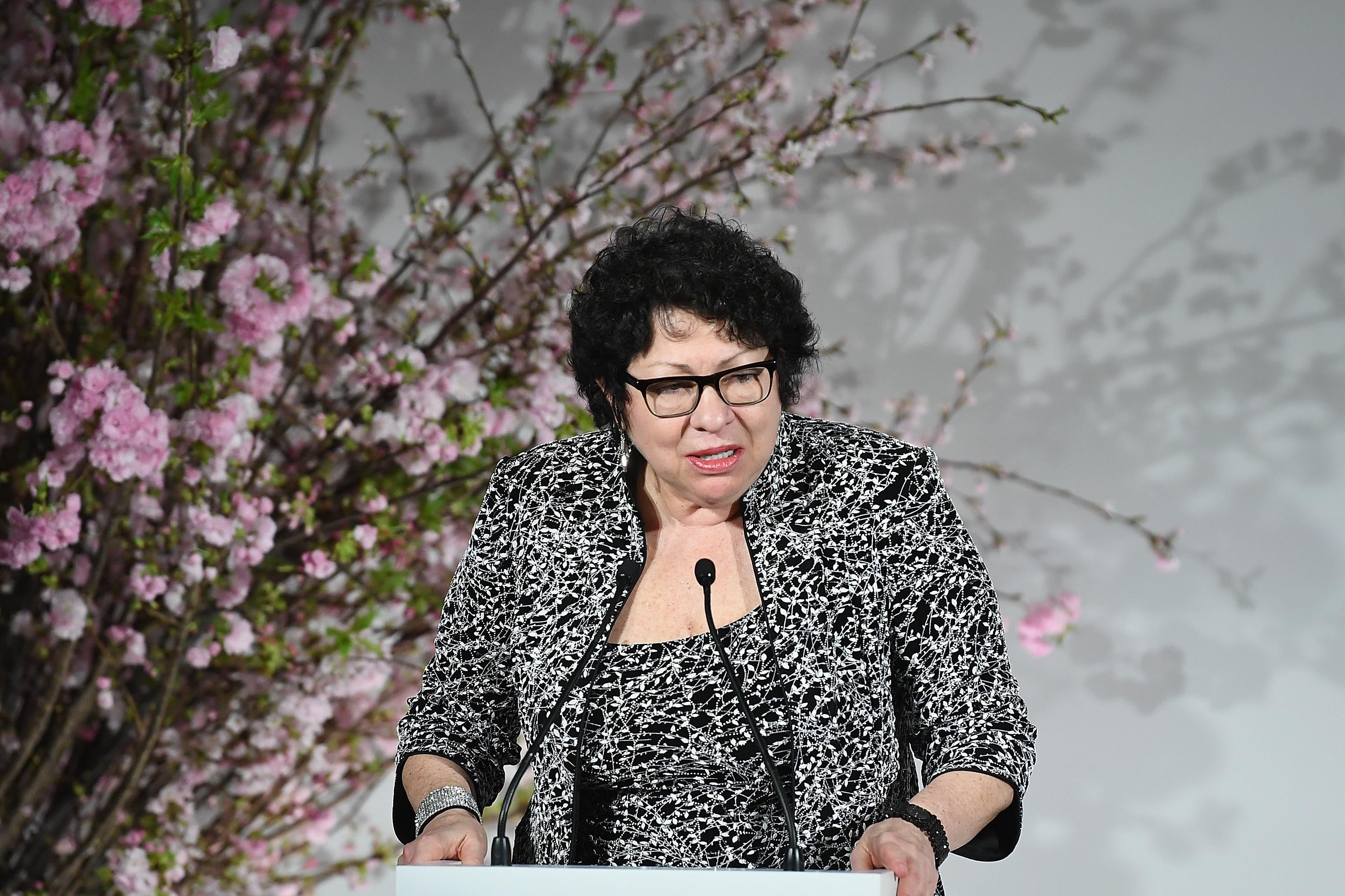 Sonia Sotomayor stands at a lectern and speaks into a microphone.