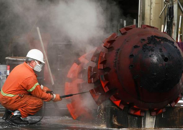 A worker uses a pressure hose to clean part of the Trans-Alaska Pipeline Marine Terminal in Valdez, Alaska, where oil flows from oil fields in Prudhoe Bay