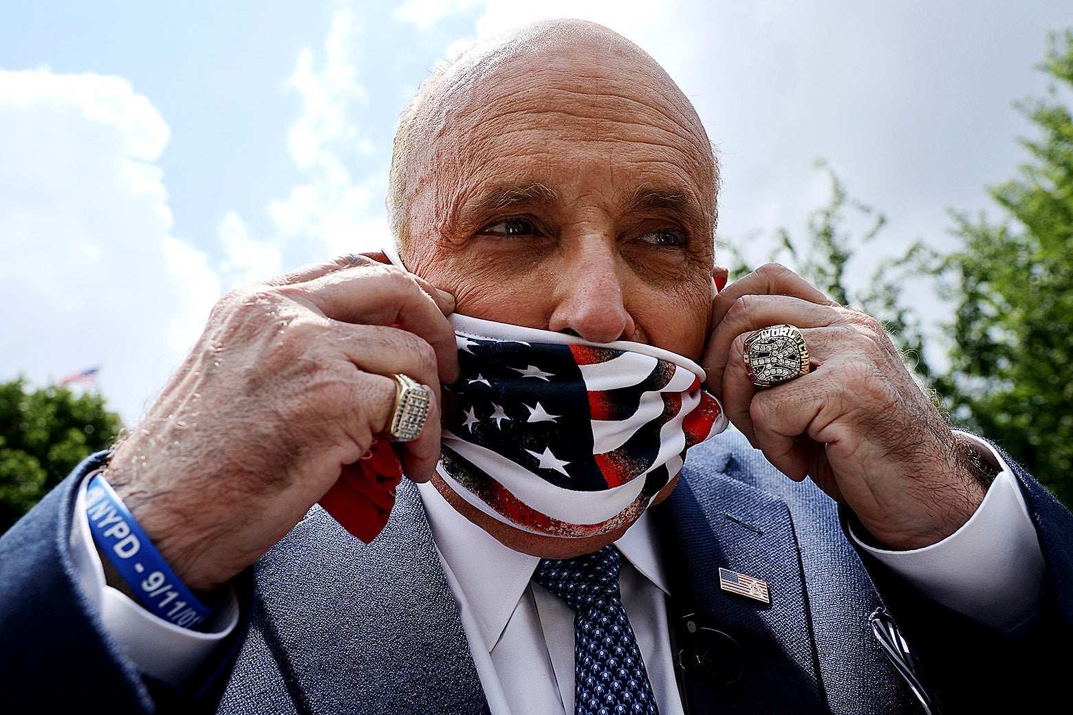 Close-up of Giuliani putting on an American flag face mask