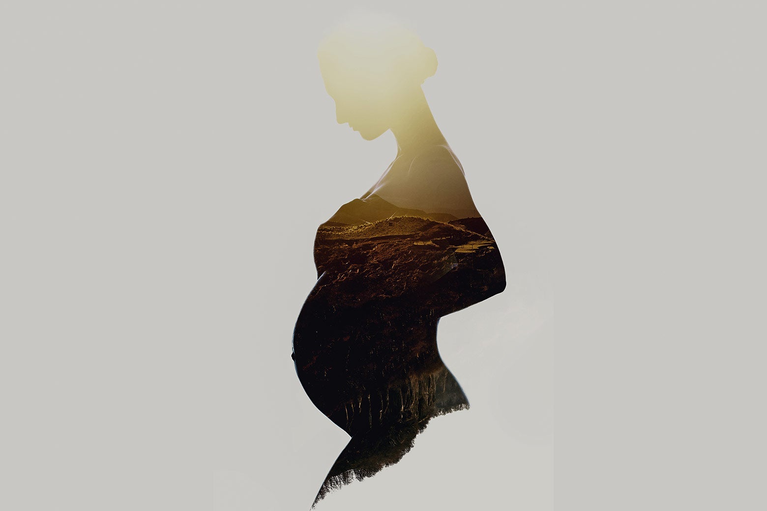 A silhouette of a visibly pregnant woman with mountains within the silhouette.