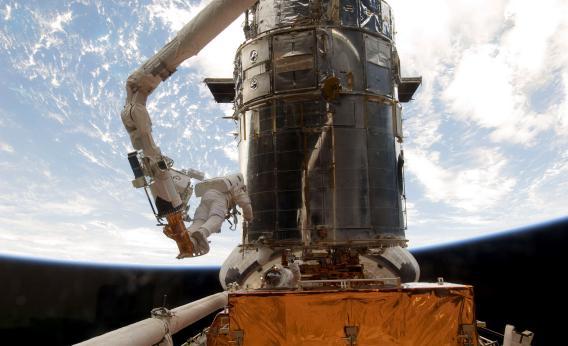 Astronauts work to refurbish and upgrade the Hubble Space Telescope.