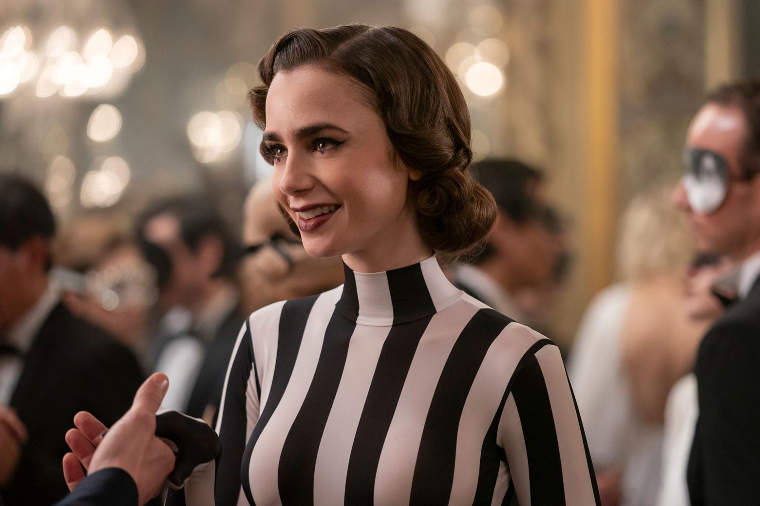 Lily Collins as Emily, dressed in a black-and-white striped gown.