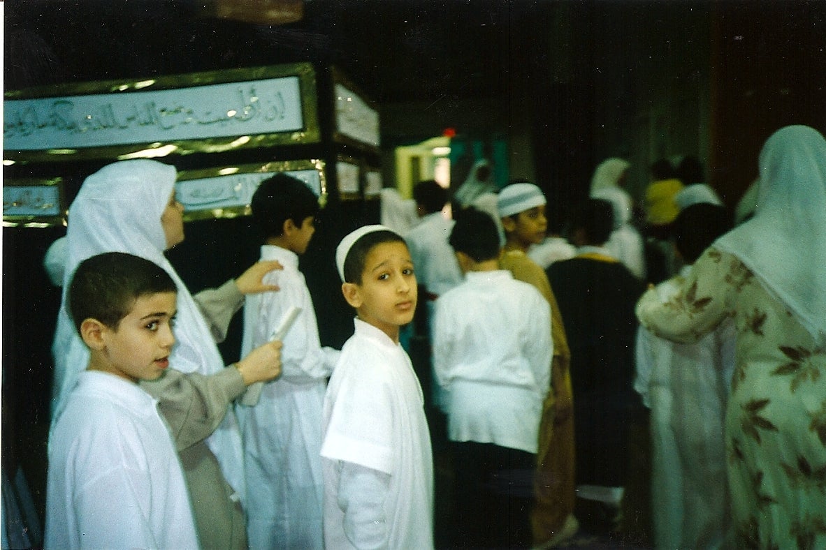Young boys dressed in white file into a gym for a practice hajj.