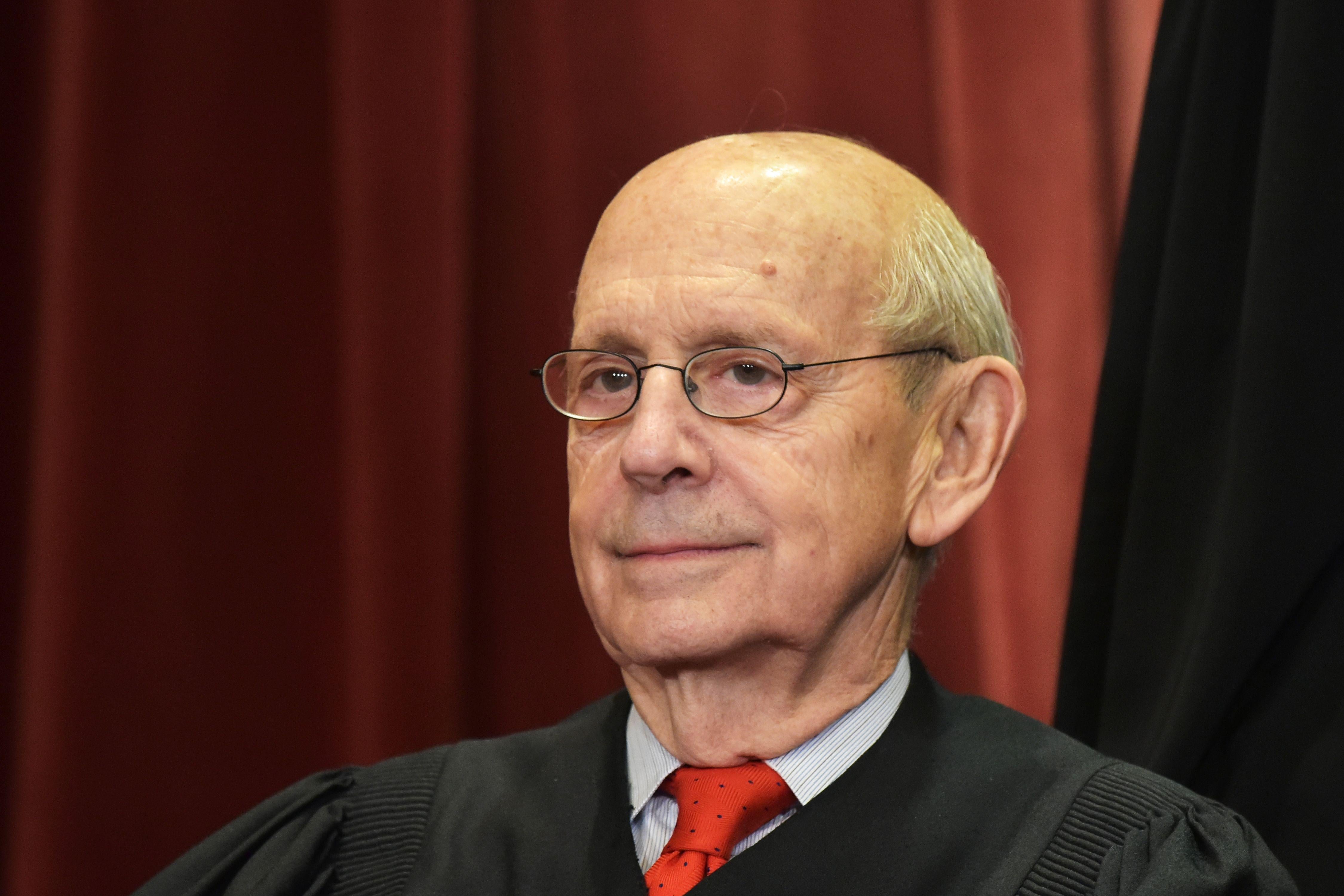 Stephen Breyer seated in a red tie and his Supreme Court justice robes