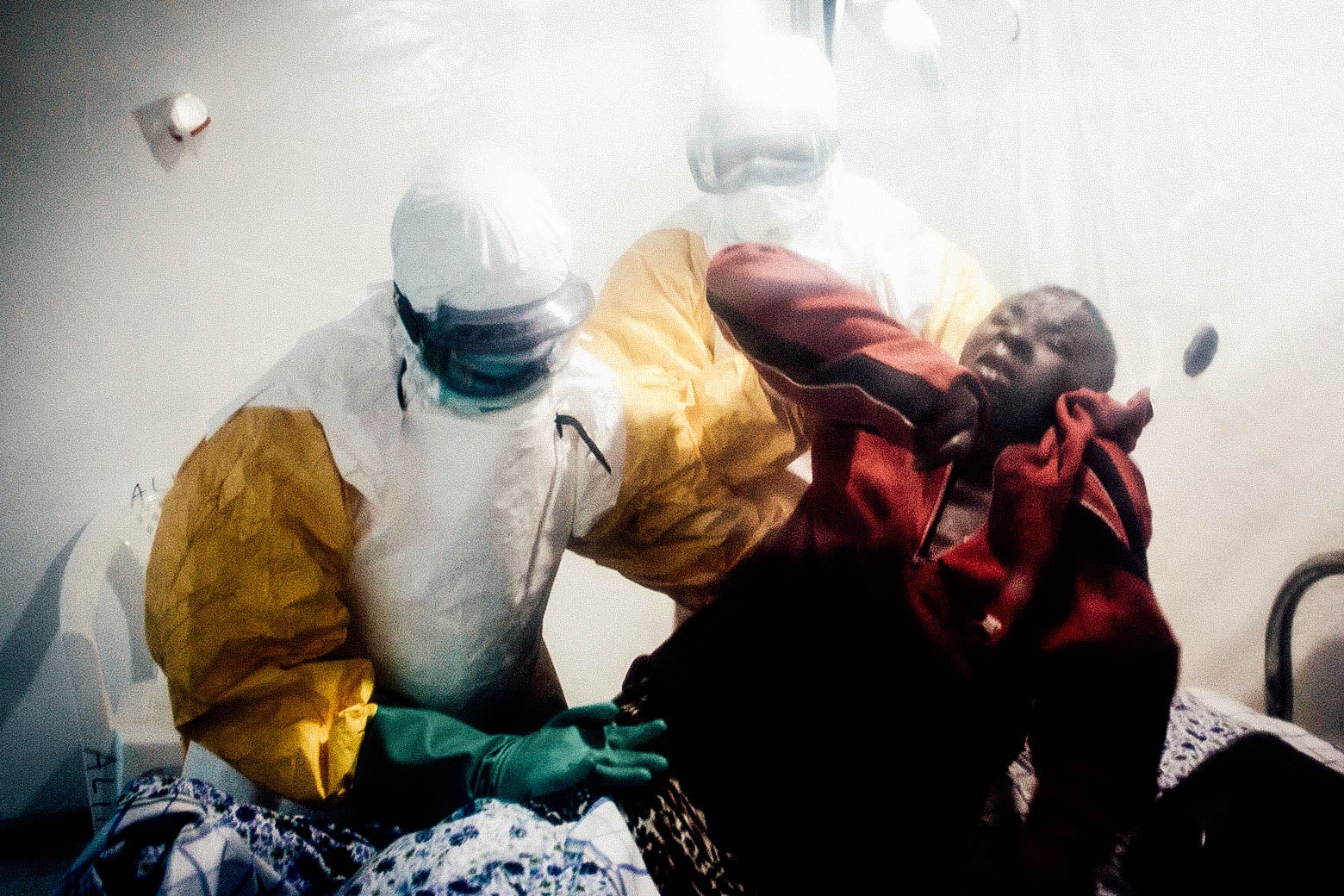 An Ebola patient is lifted up by two medical workers after being admitted into a Biosecure Emergency Care Unit on Aug. 15 in Beni.