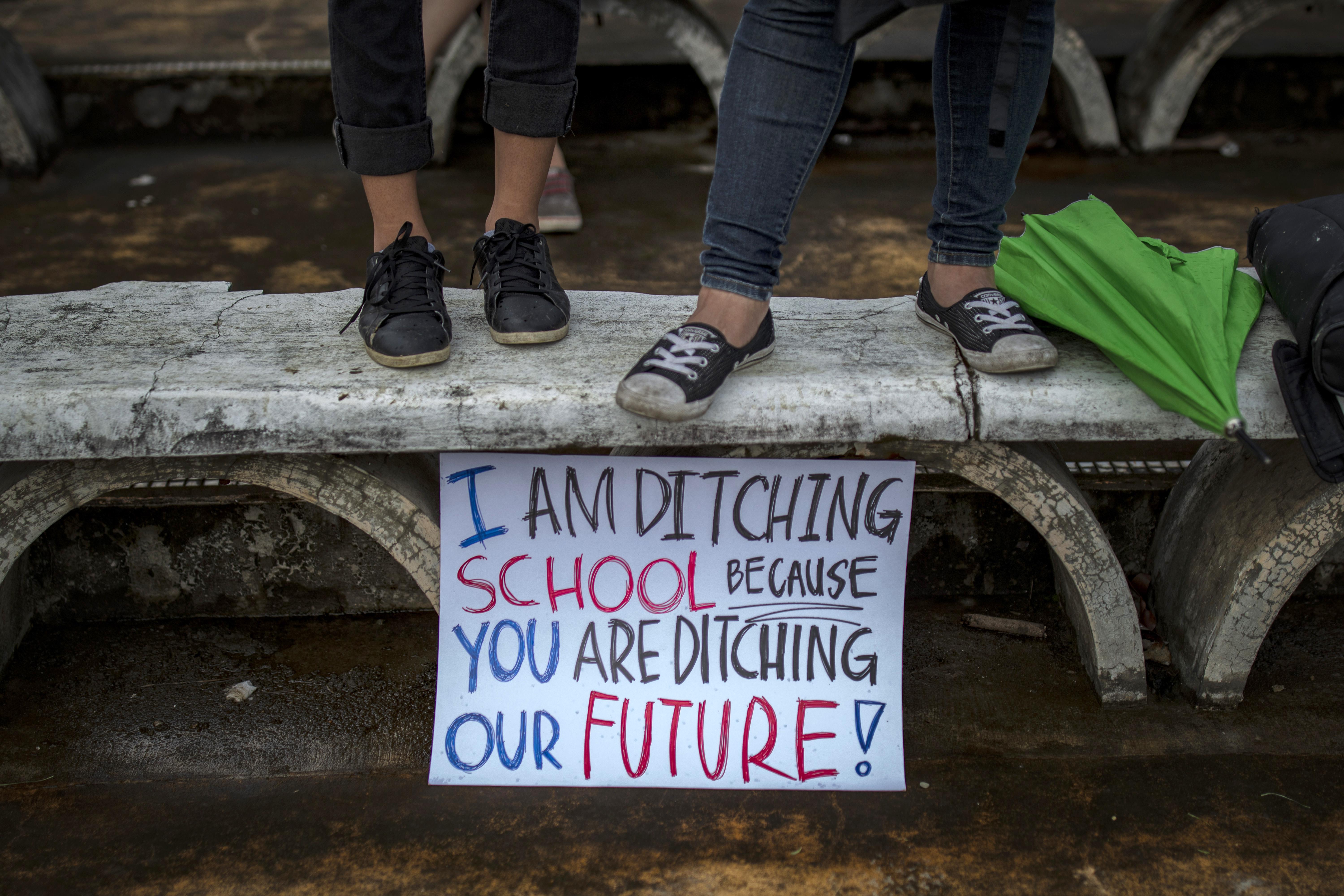 Filipino students stand over a sign that says "I am ditching school because you our ditching our future."