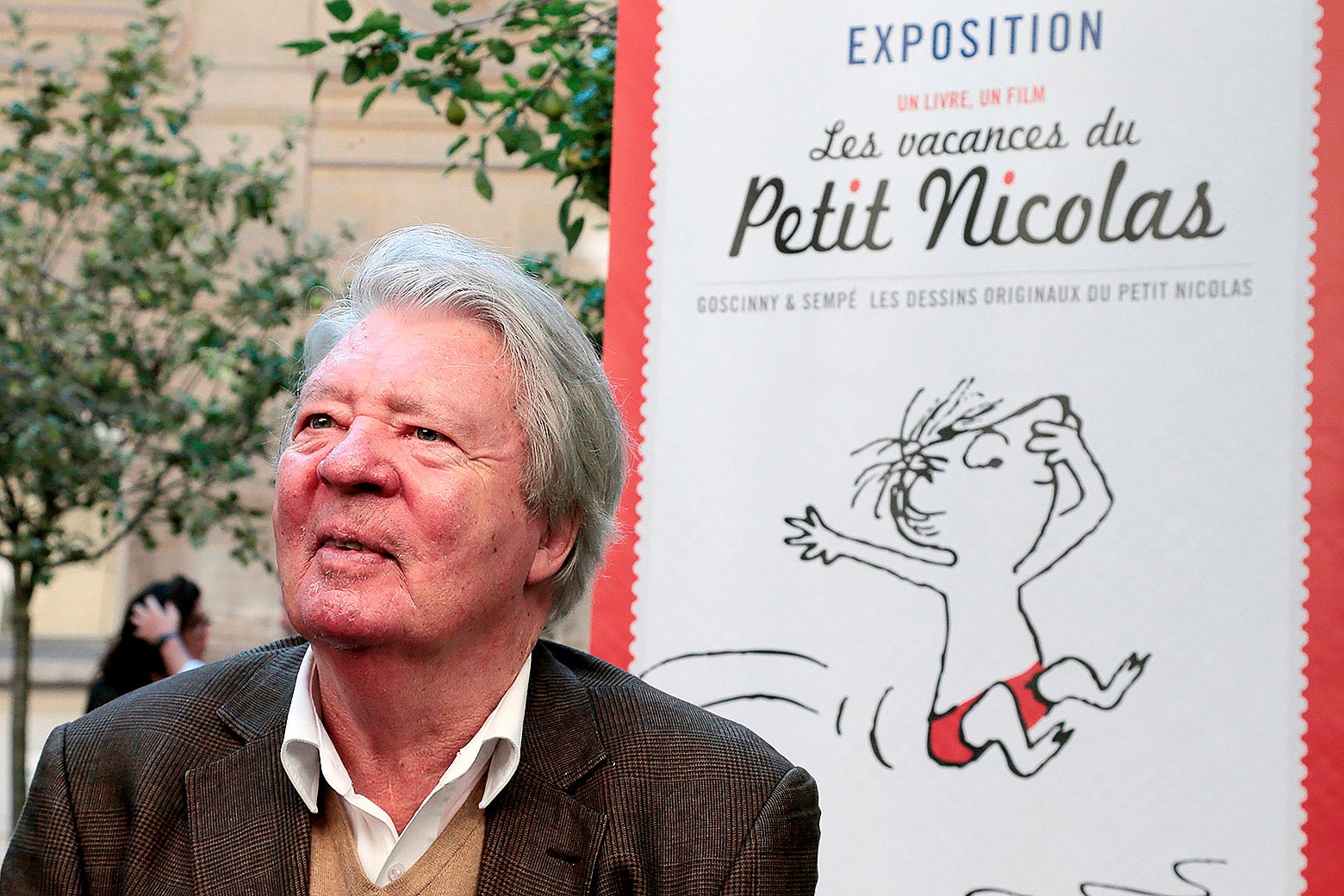 Jean-Jacques Sempe poses next to a poster presenting an exhibition dedicated to the Petit Nicolas children's books series in 2014.