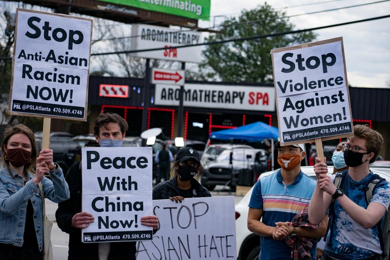 Protesters hold up signs that say things like, "Stop anti-Asian racism now" and "Stop violence against women."