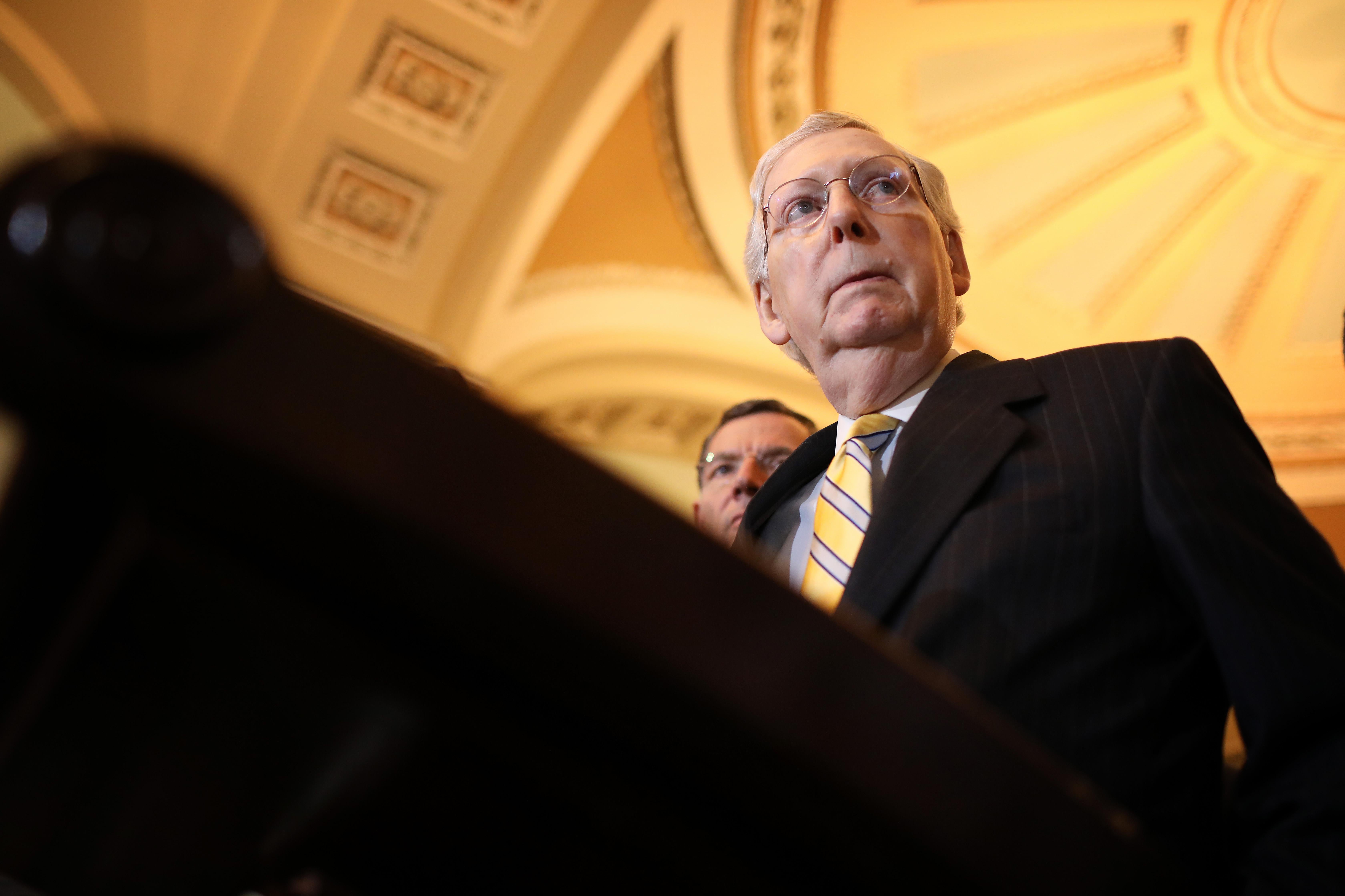 Mitch McConnell stands at a podium, with the ceiling of the U.S. Capitol in the background.