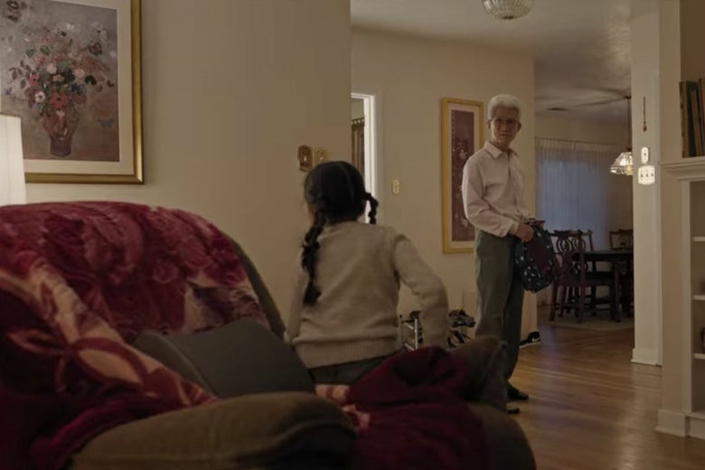 Ju Ju sits on a big chair and her grandfather stands a few feet away.