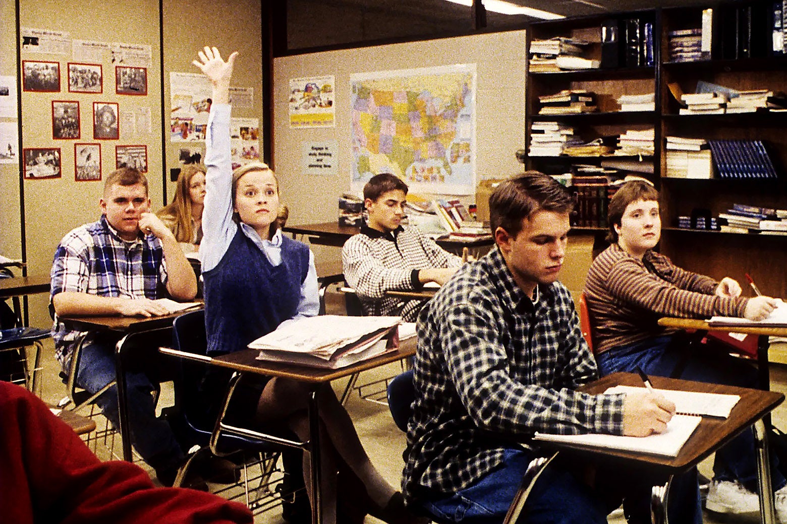 Reese Witherspoon raising her hand in the middle of a full classroom