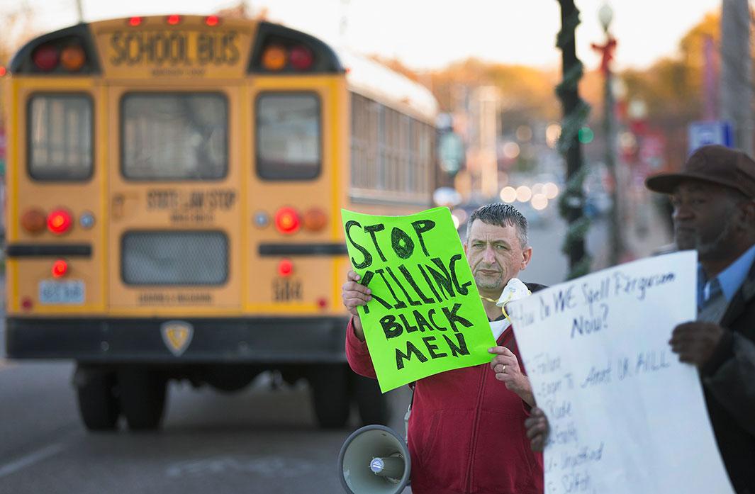 A school bus passes demonstrators protesting outside the police station on Nov. 10, 2014, in Ferguson, Missouri. As the suburb prepares for the grand jury decision in the shooting death of Michael Brown, school leaders have urged officials to announce the finding outside of school hours so that children will not be at risk of being caught up in rioting if it occurs. The grand jury’s decision is expected sometime in November 