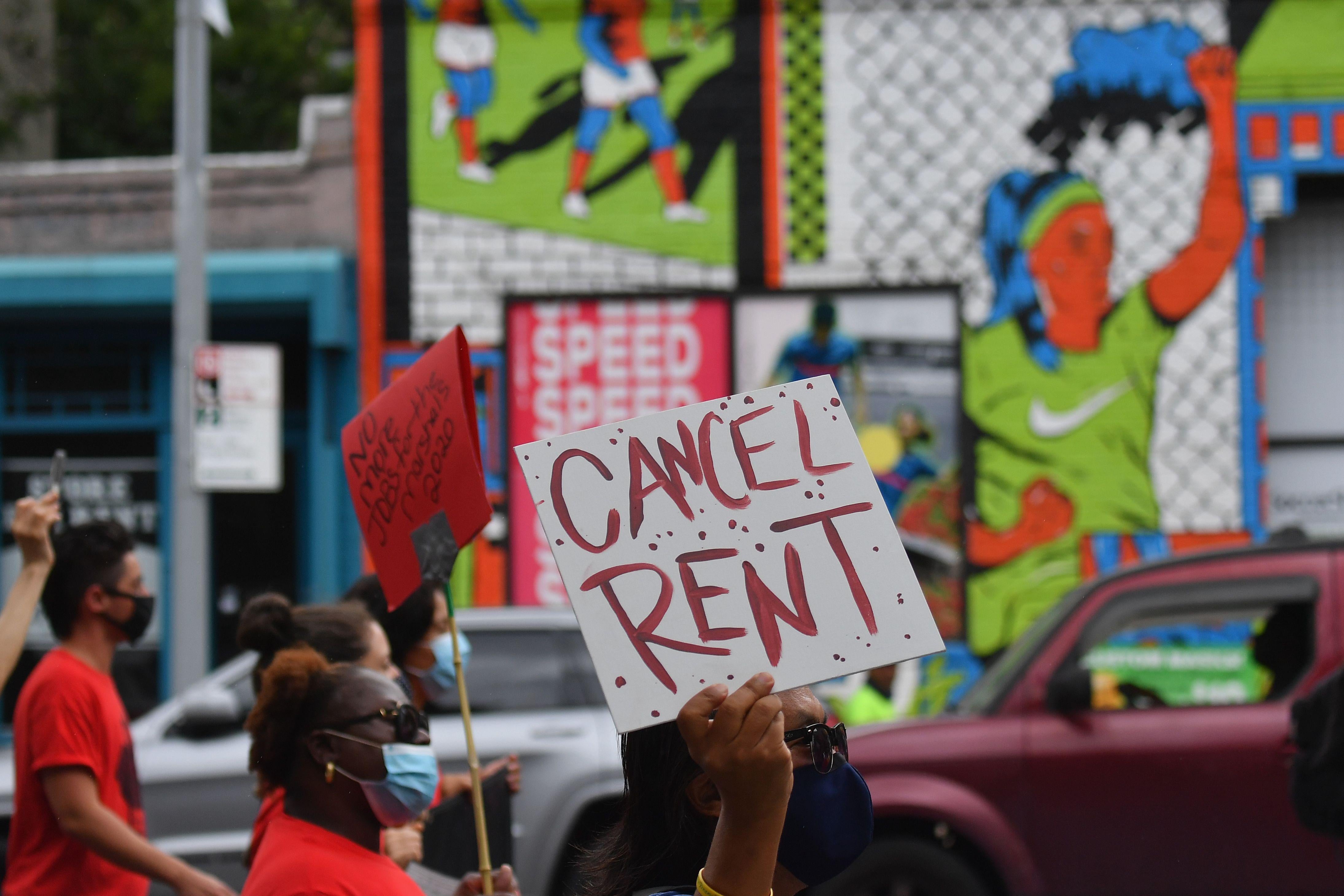 In a protest, a hand holds up a sign saying "Cancel Rent."