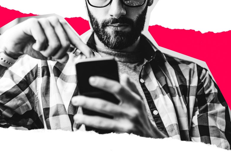 A man with glasses and a beard man taps at something on his phone.