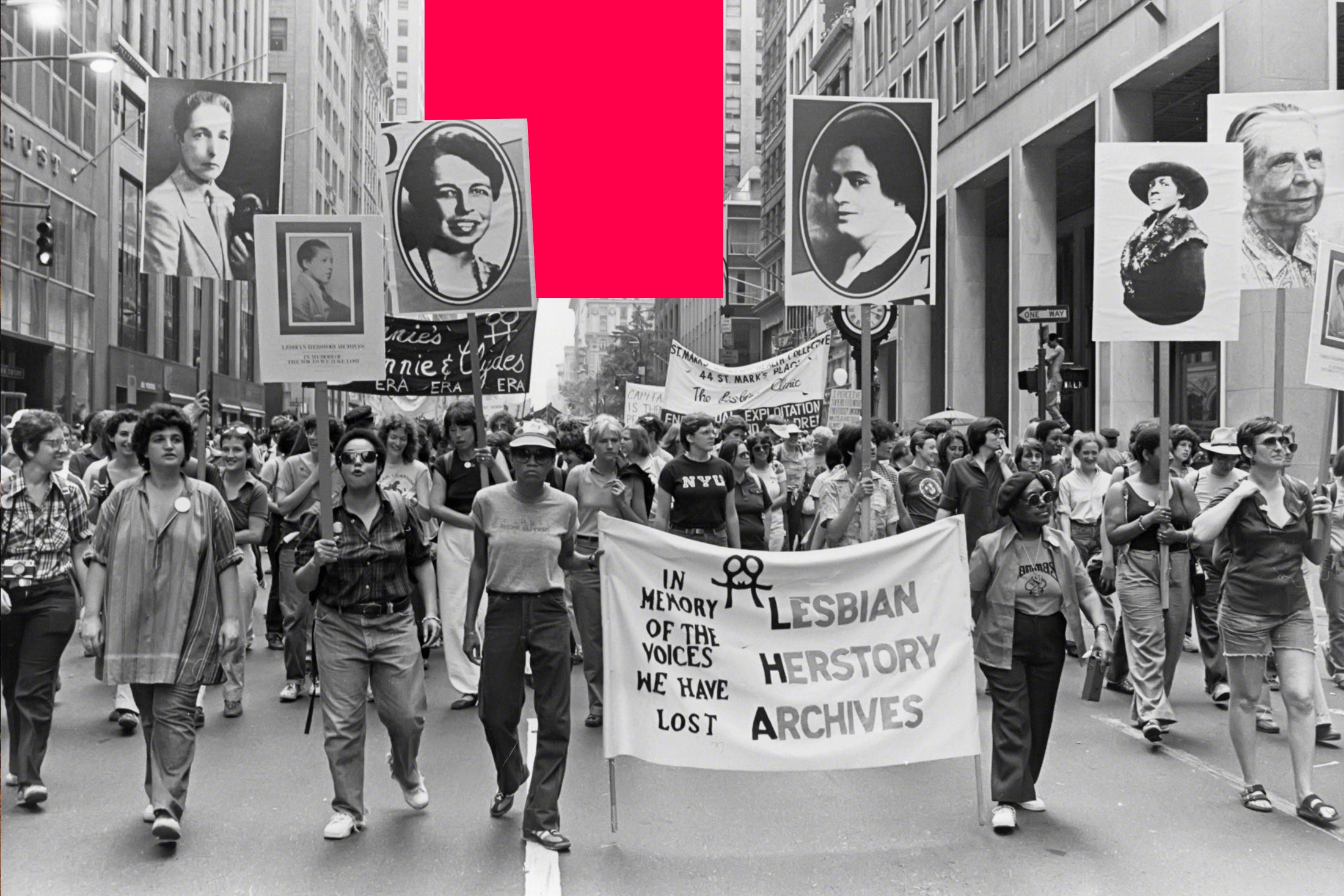 People marching in the Pride Parade circa 1980 in New York City. In the center, two people hold a banner for Lesbian Herstory Archives; others hold up posters of LGBTQ icons.