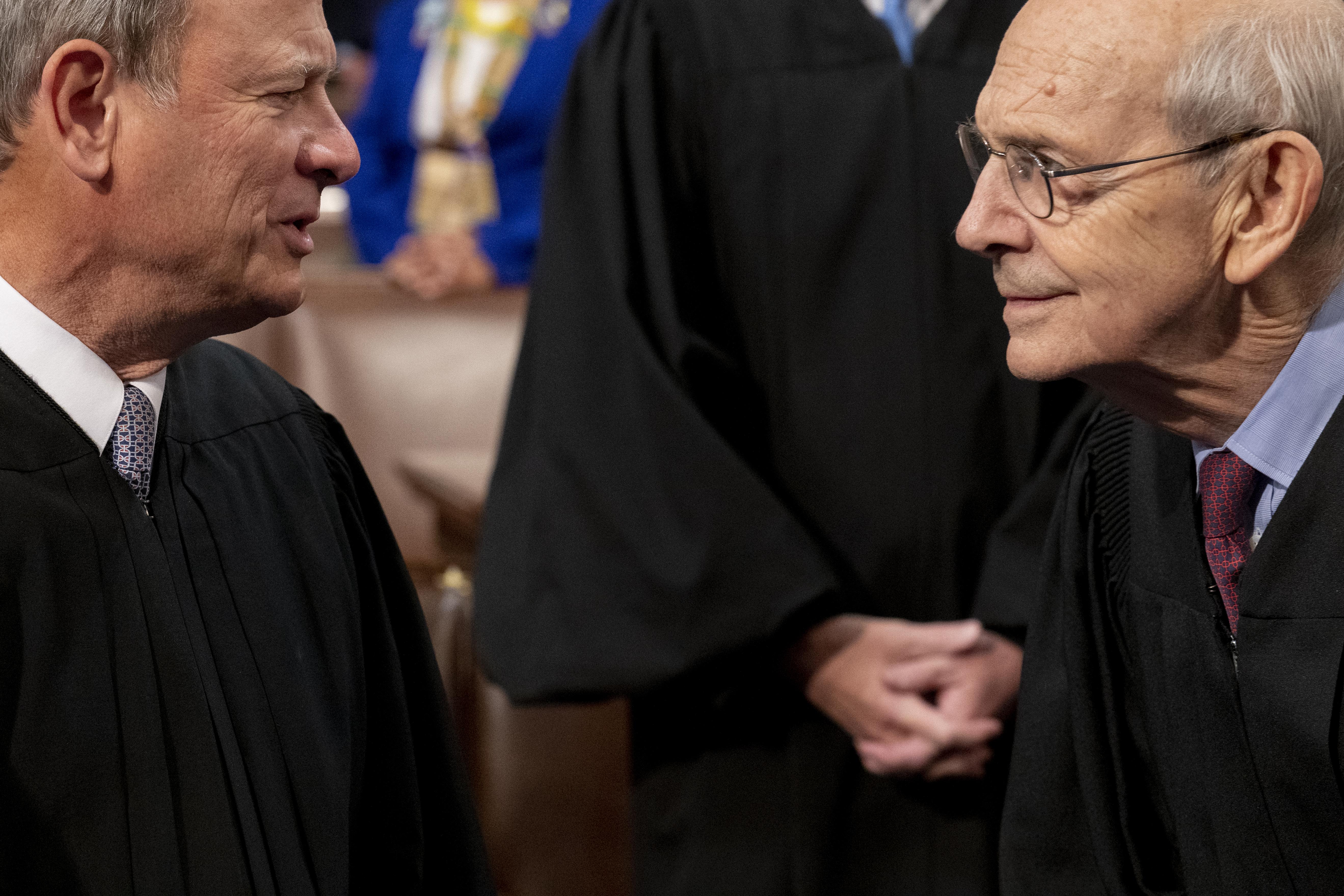 John Roberts and Stephen Breyer confer, leaning in toward each other.
