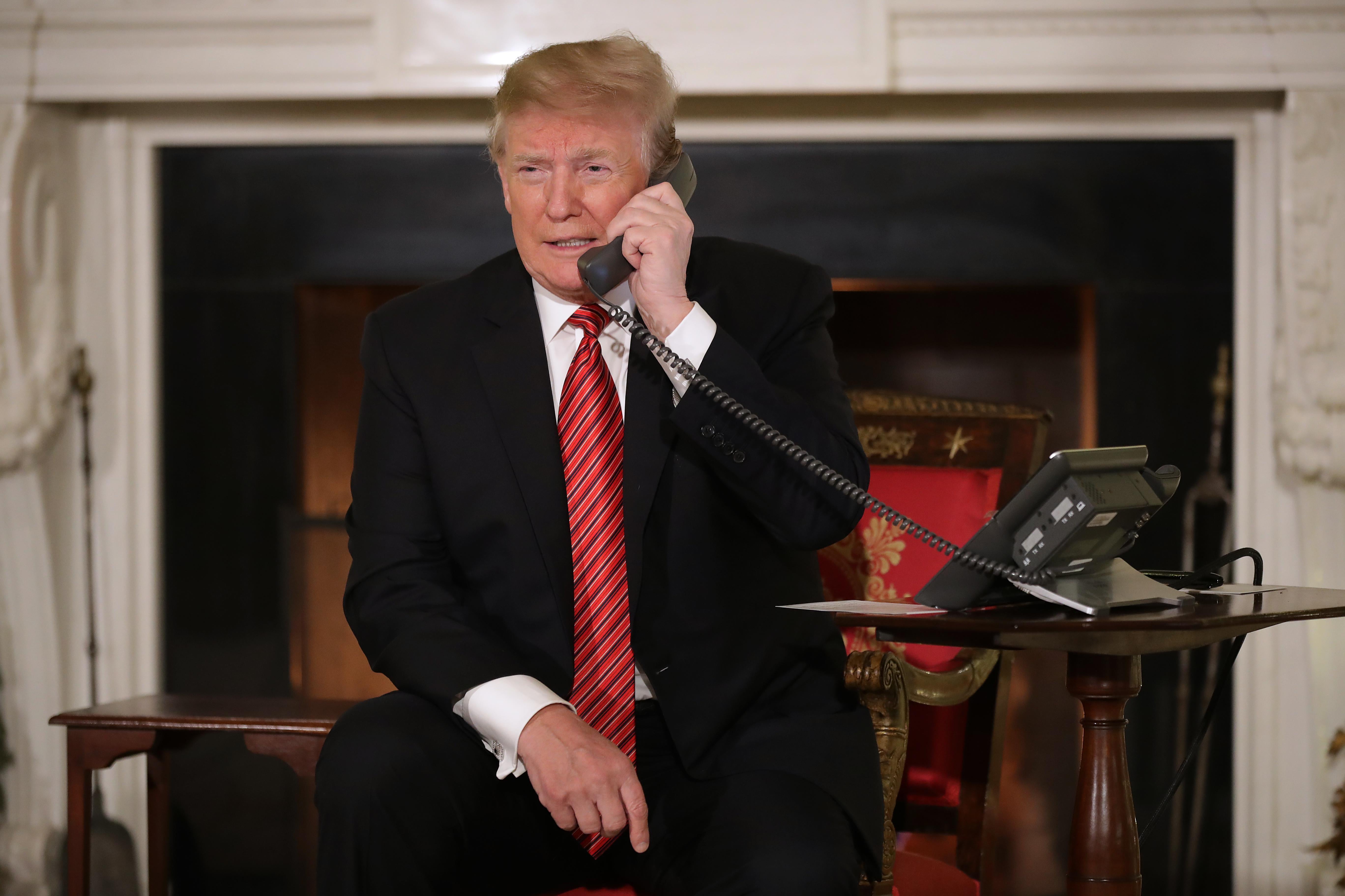 Trump holding a phone to his ear as he takes calls from children in the East Room of the White House for a Santa Claus event on Dec. 24, 2018.