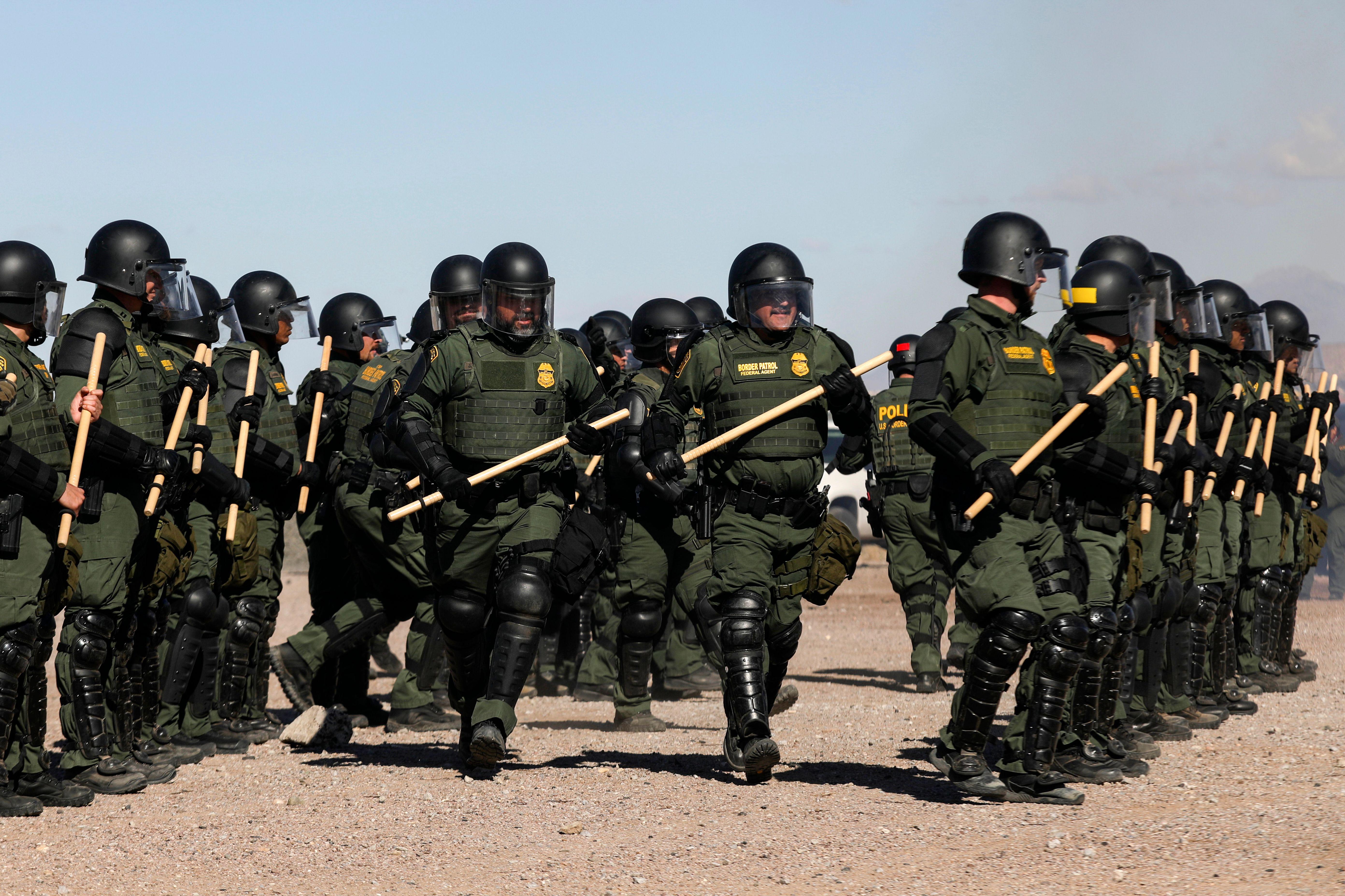 U.S. Border Patrol Agents, wearing uniforms and helmets and carrying batons