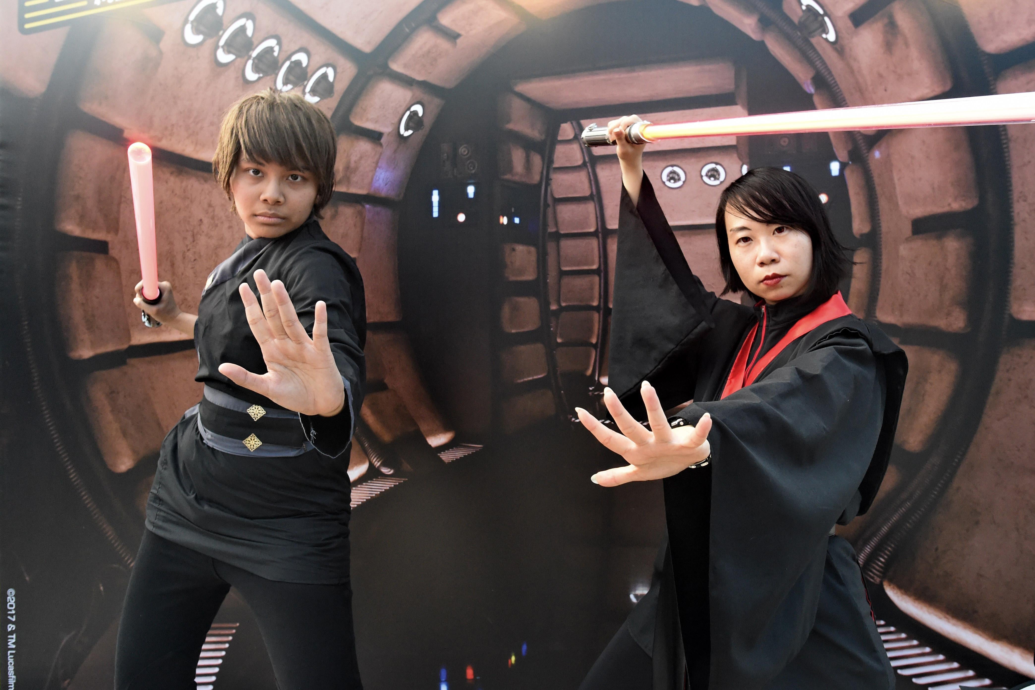 Two people in robes wield lightsabers.