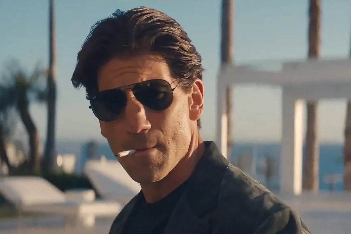 A man smoking a cigarette and wearing sunglasses. 