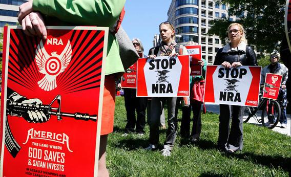 Anti-gun activists hold up signs against guns and the NRA while in McPherson Square in Washington April 25, 2013.      