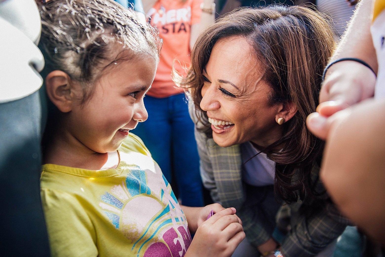 Sen. Kamala Harris smiles and leans down to talk to a young immigrant child. 