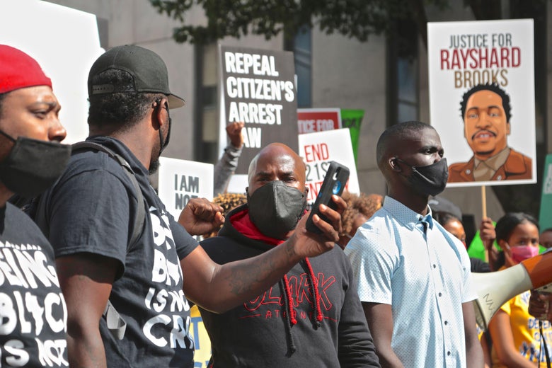 A crowd of protesters hold up signs demanding justice for Rayshard Brooks
