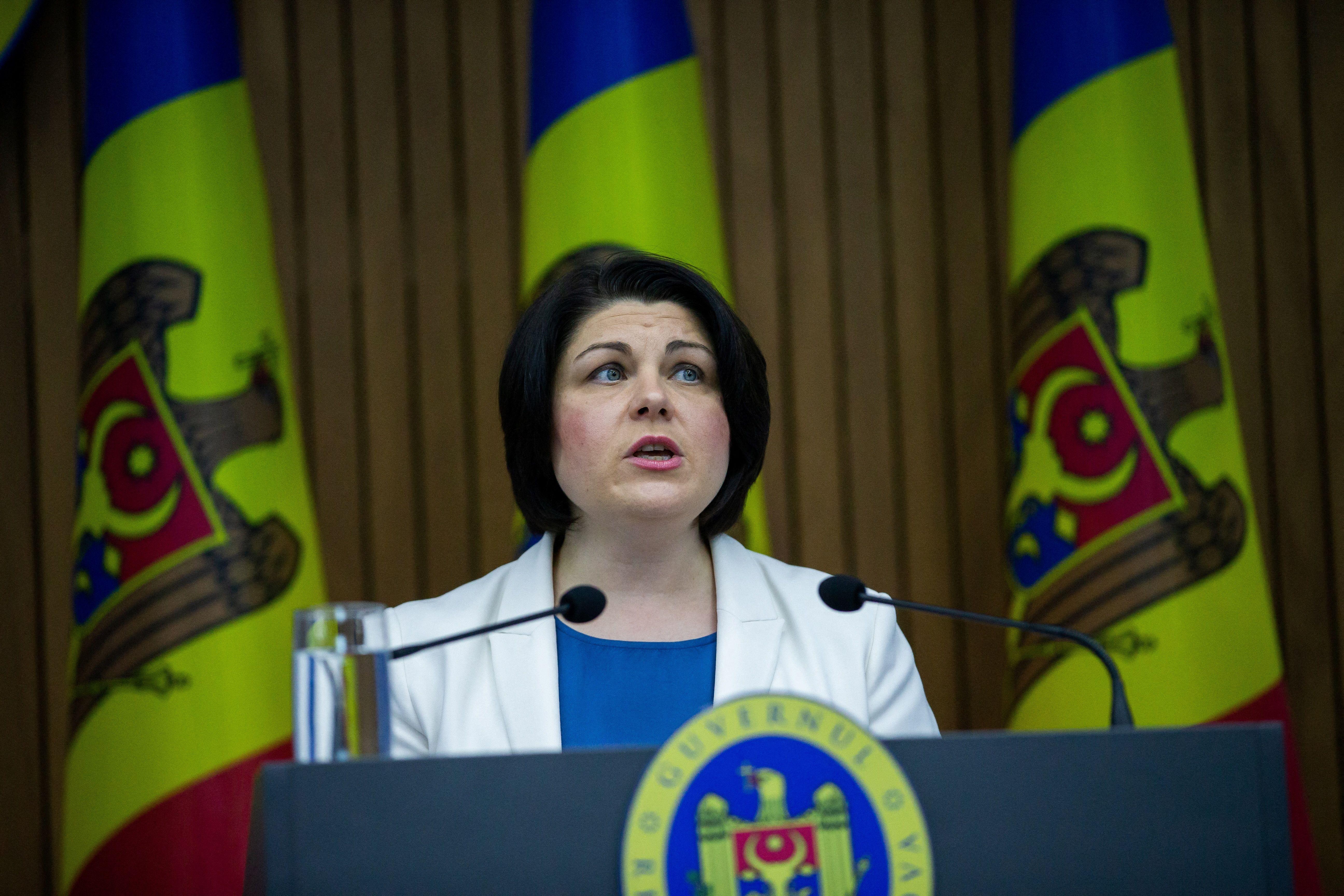 Natalia Gavrilita speaks at a lectern in front of three Moldovan flags.