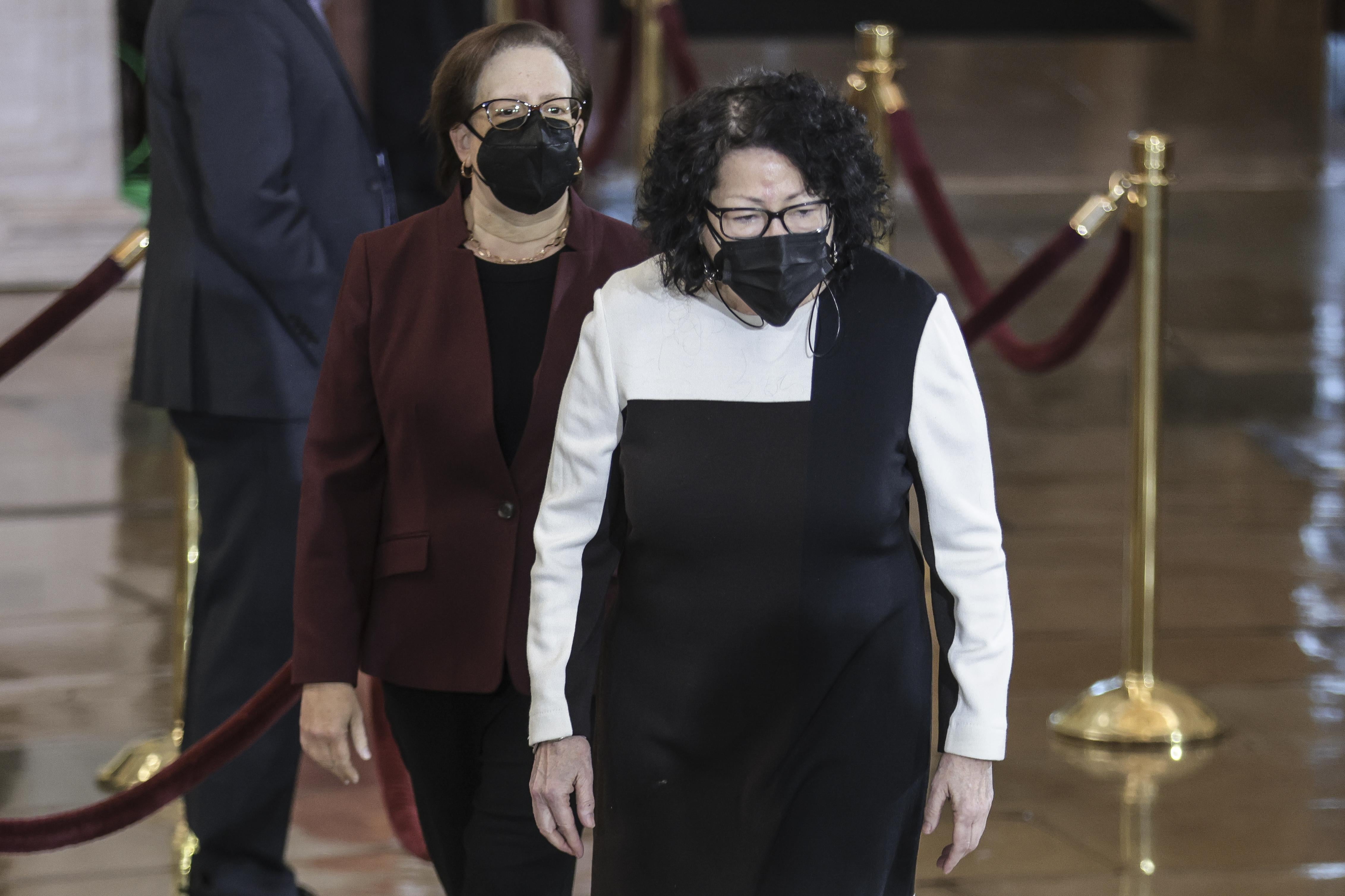 Elena Kagan and Sonia Sotomayor looking somber and wearing masks in the rotunda
