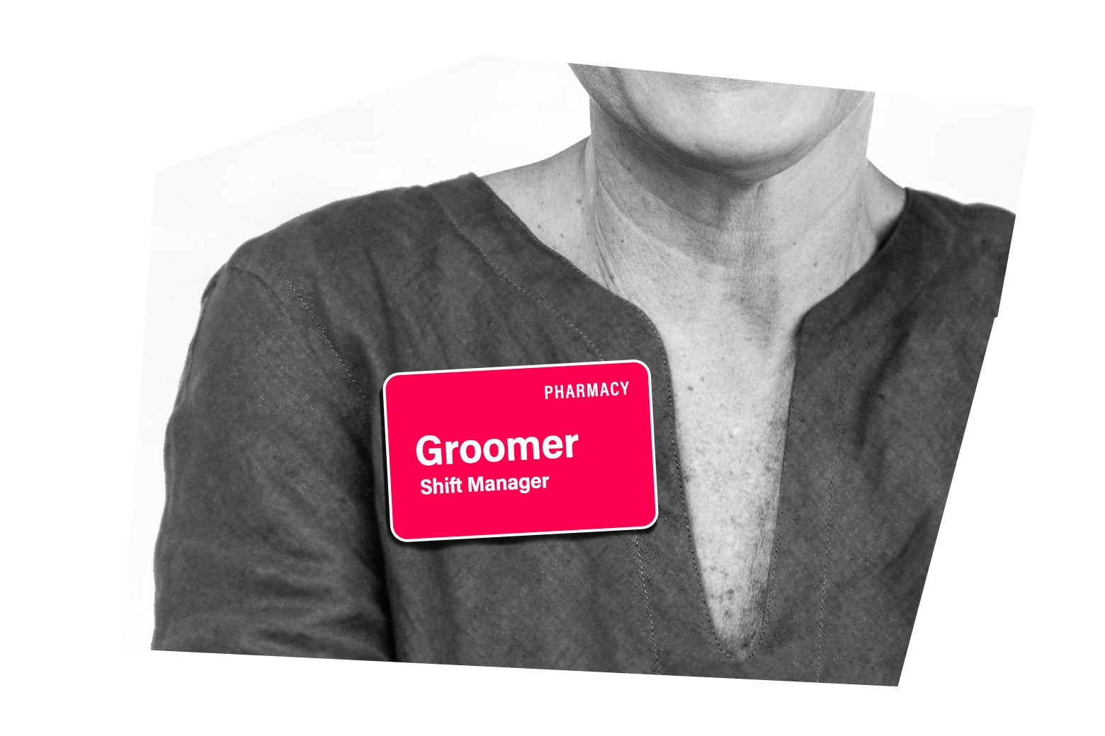 A person wearing a shift manager name tag with the word "groomer" on it.