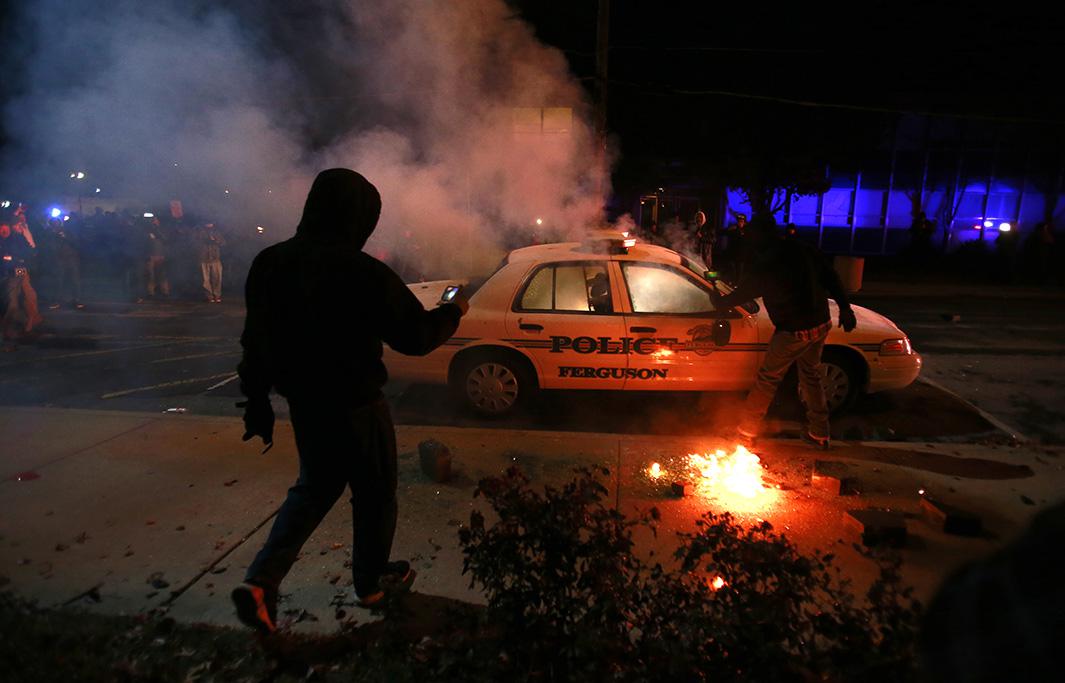 A protester videos a police car set on fire by protesters in Ferguson, Missouri, Nov. 25, 2014