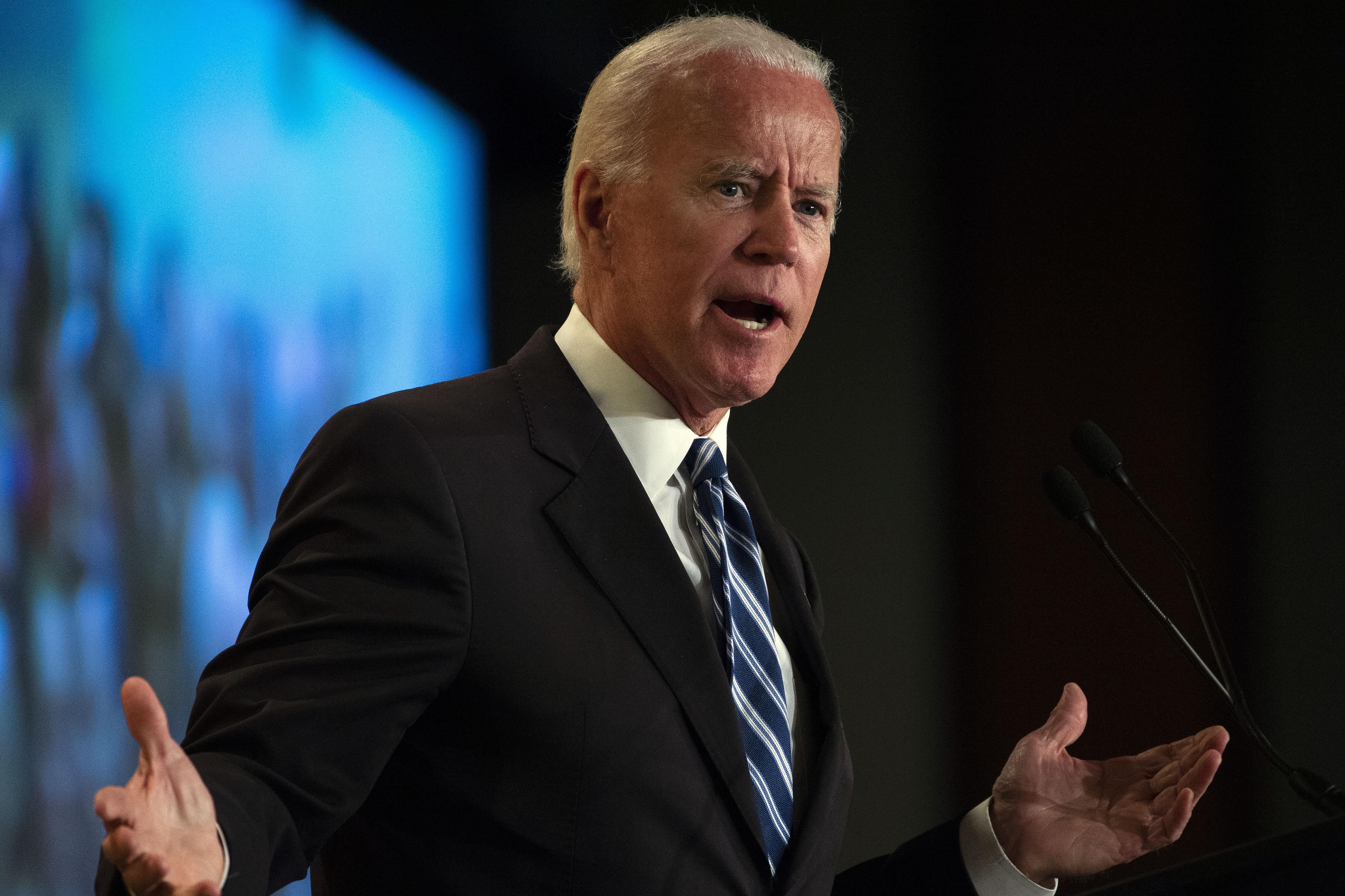 Joe Biden shrugs while speaking at a podium.