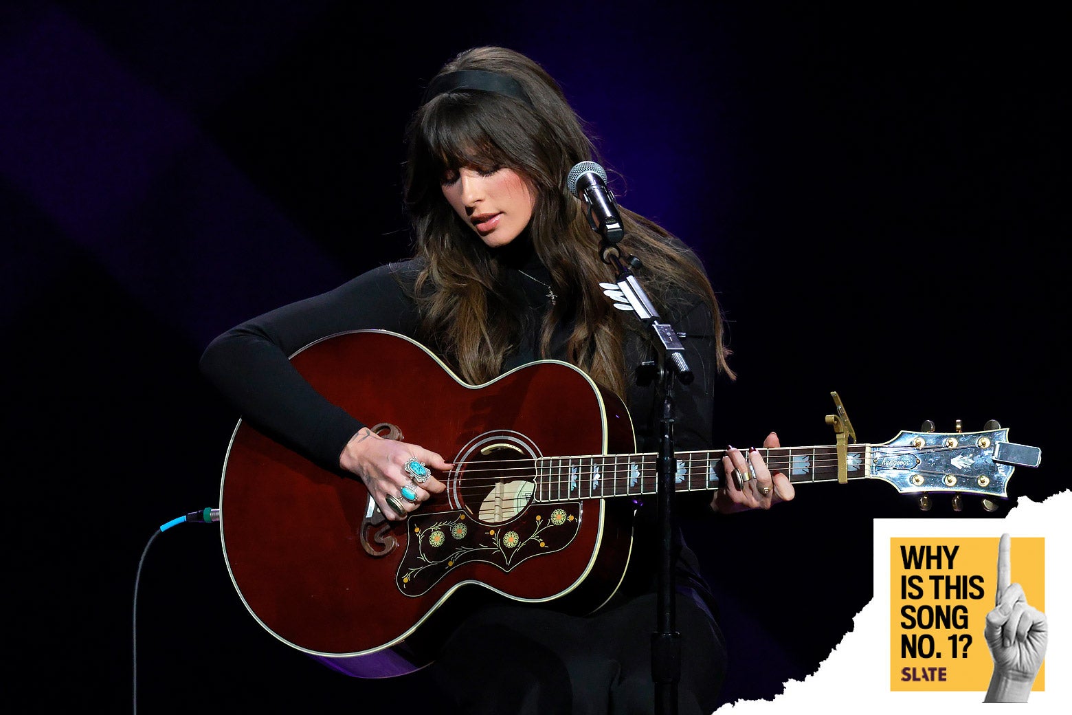 Langley seated playing guitar.