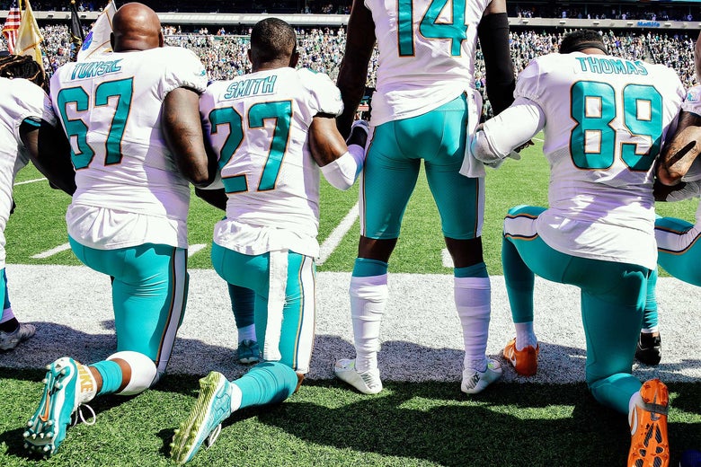 Miami Dolphins Laremy Tunsil, Maurice Smith, and Julius Thomas kneel as Jarvis Landry stands on the sidelines.