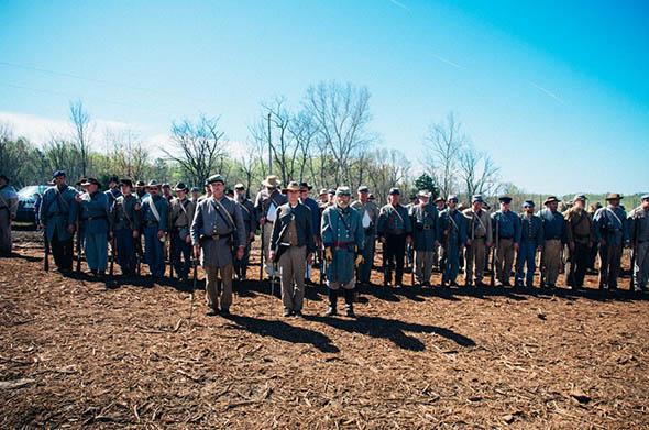 A large group of Confederate re-enactors face inspection from their “officers” before a march.