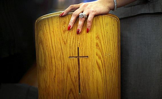 A Christian women holds onto a pew.