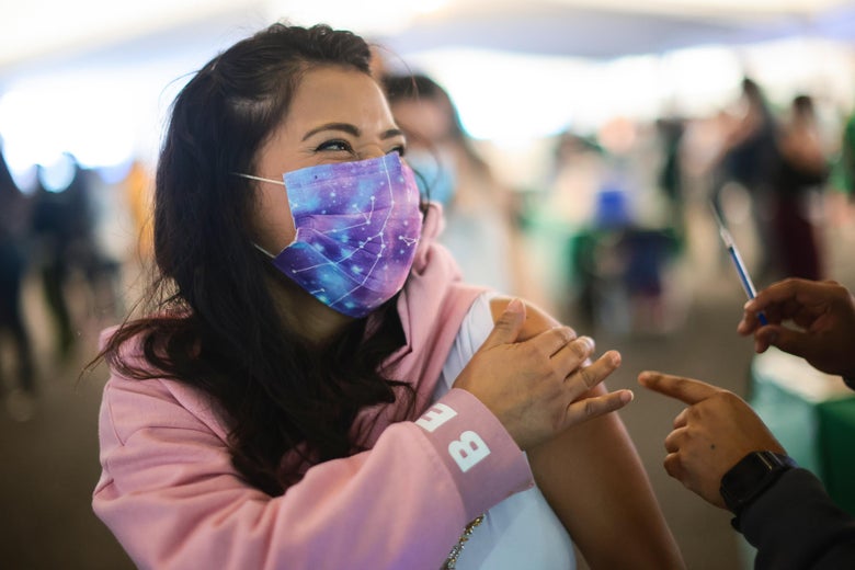 A woman with a galaxy-pattern face mask receives a coronavirus vaccine from a nurse off-screen at a vaccination site in Mexico City, Mexico.
