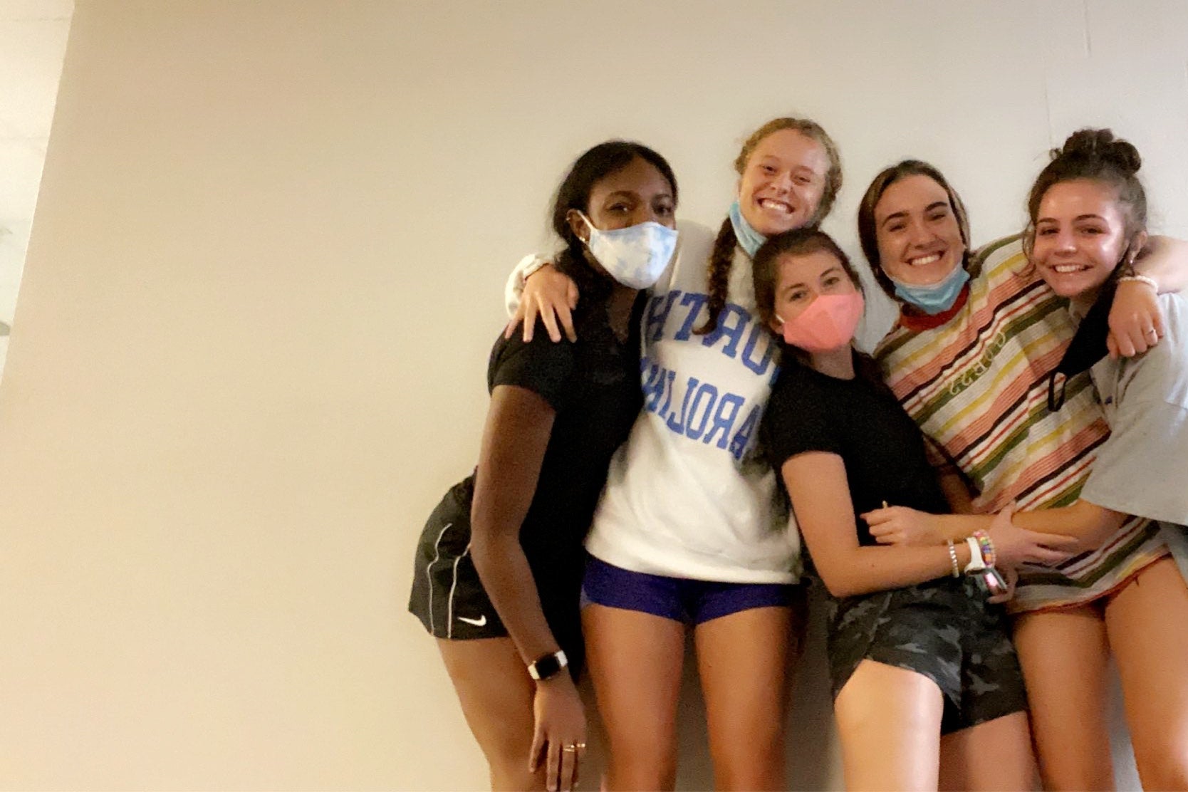 College girls, some wearing masks, posing for a picture.