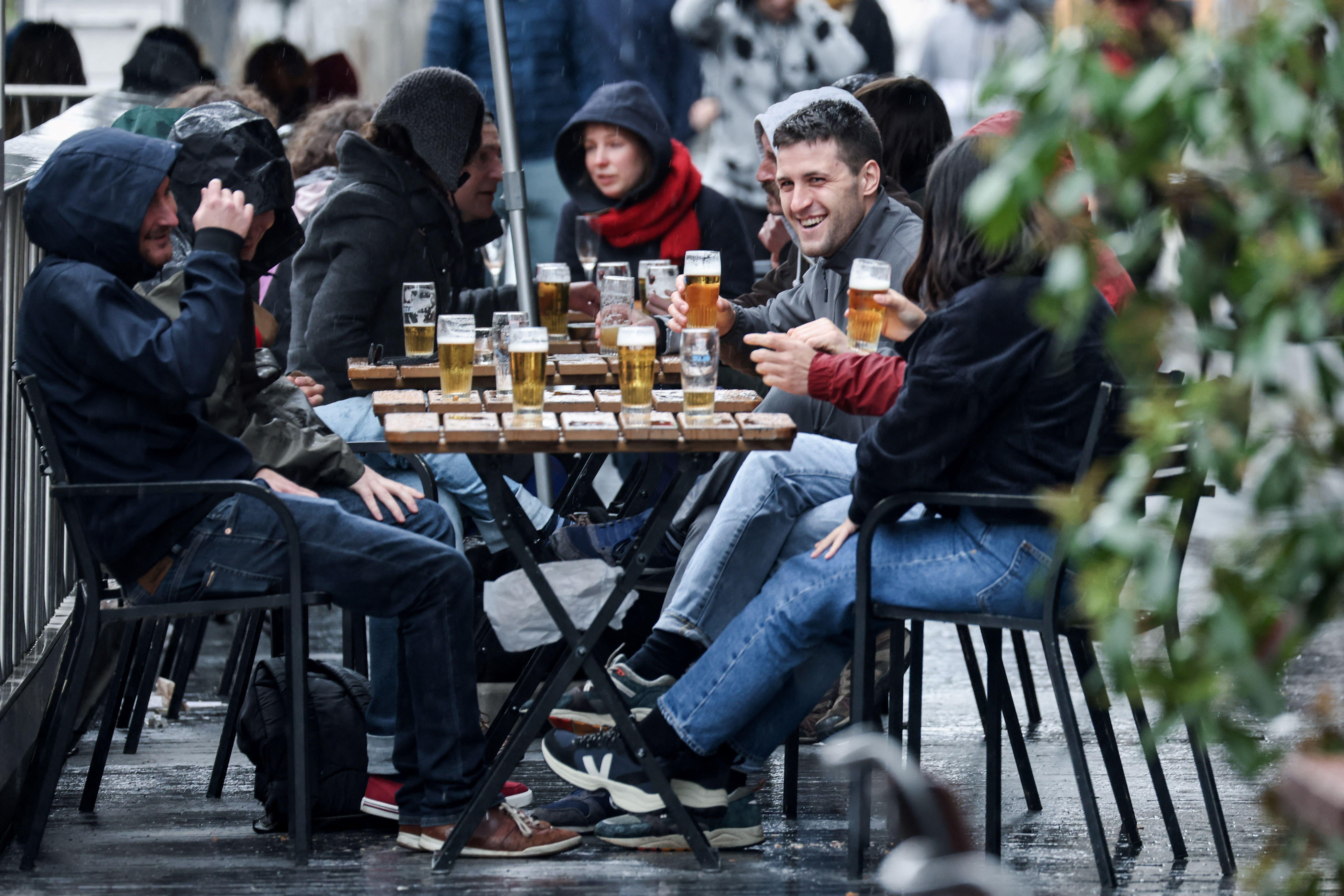 Friends sit at a table drinking beer on a terrace.
