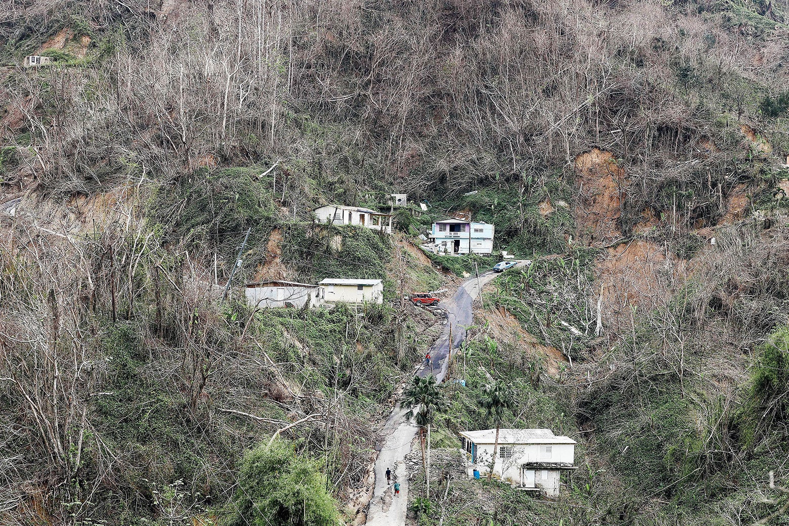 Community members walk on the street in a devastated section nearly three weeks after Hurricane Maria hit the island, on Oct. 10, 2017, in Pellejas, Adjuntas municipality, Puerto Rico.