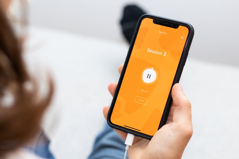 A hand holding a phone with the Headspace app