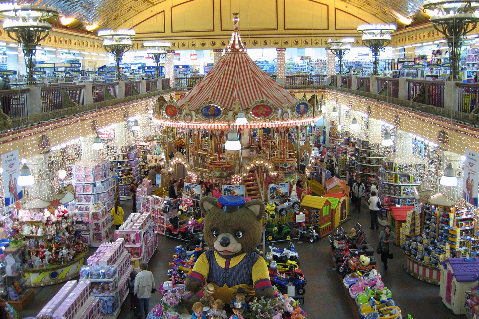 The interior of the Detsky Mir department store, featuring a merry-go-round and a giant teddy bear.