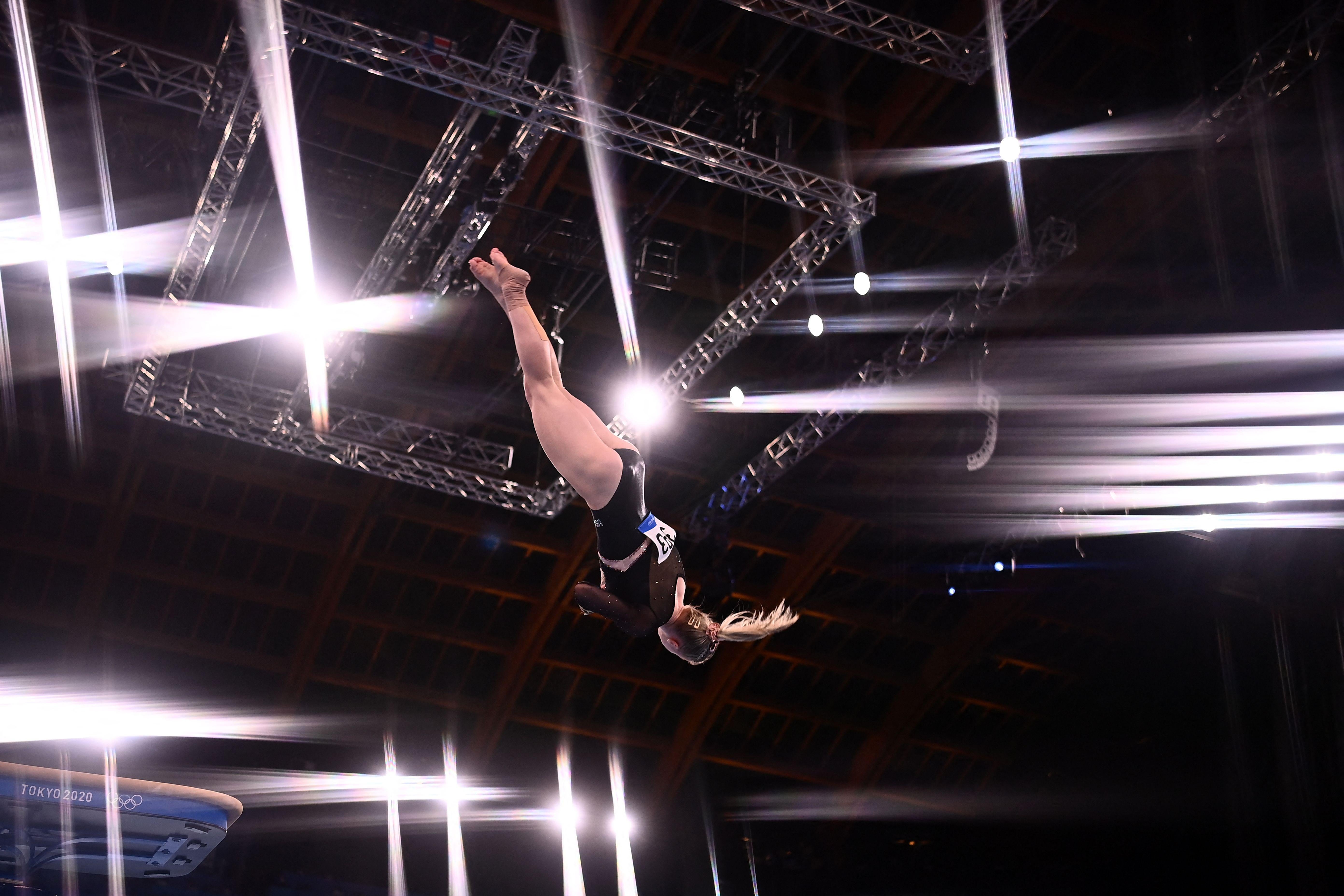 Carey twists upside down in midair, with the stadium lights flashing and beaming all around her