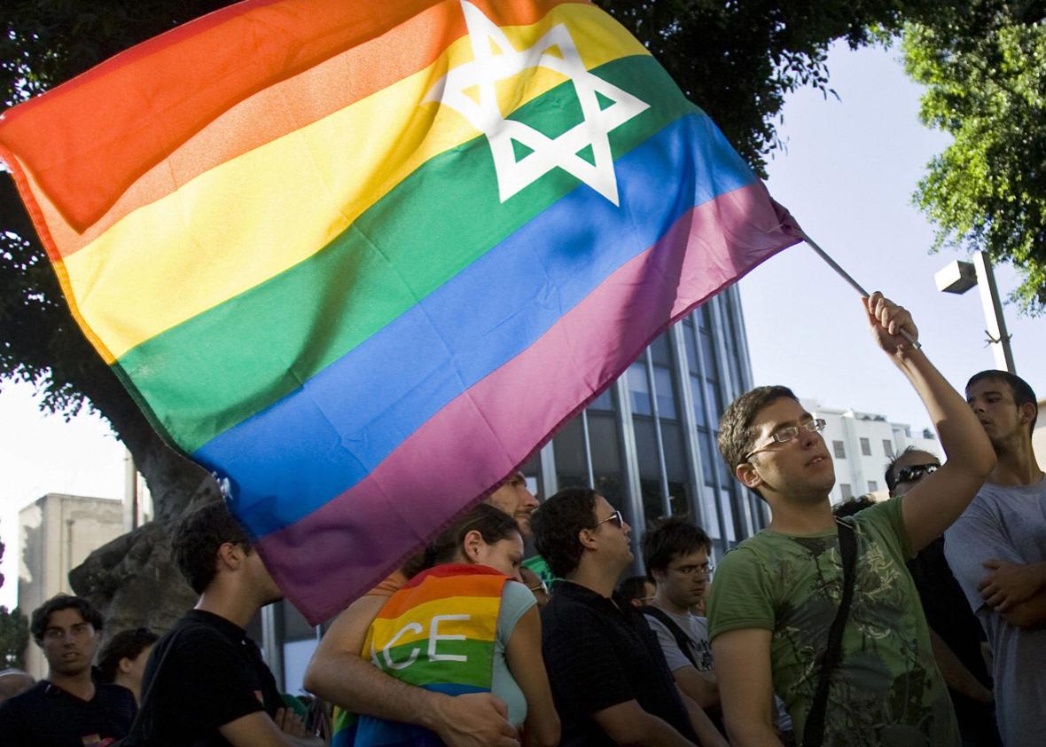 An Israeli man waves a rainbow flag bearing the Star of David 