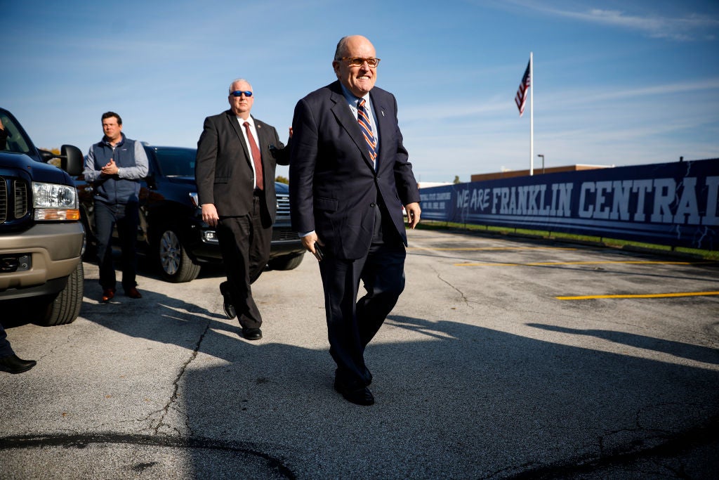 Giuliani walks through a parking lot after exiting an SUV.