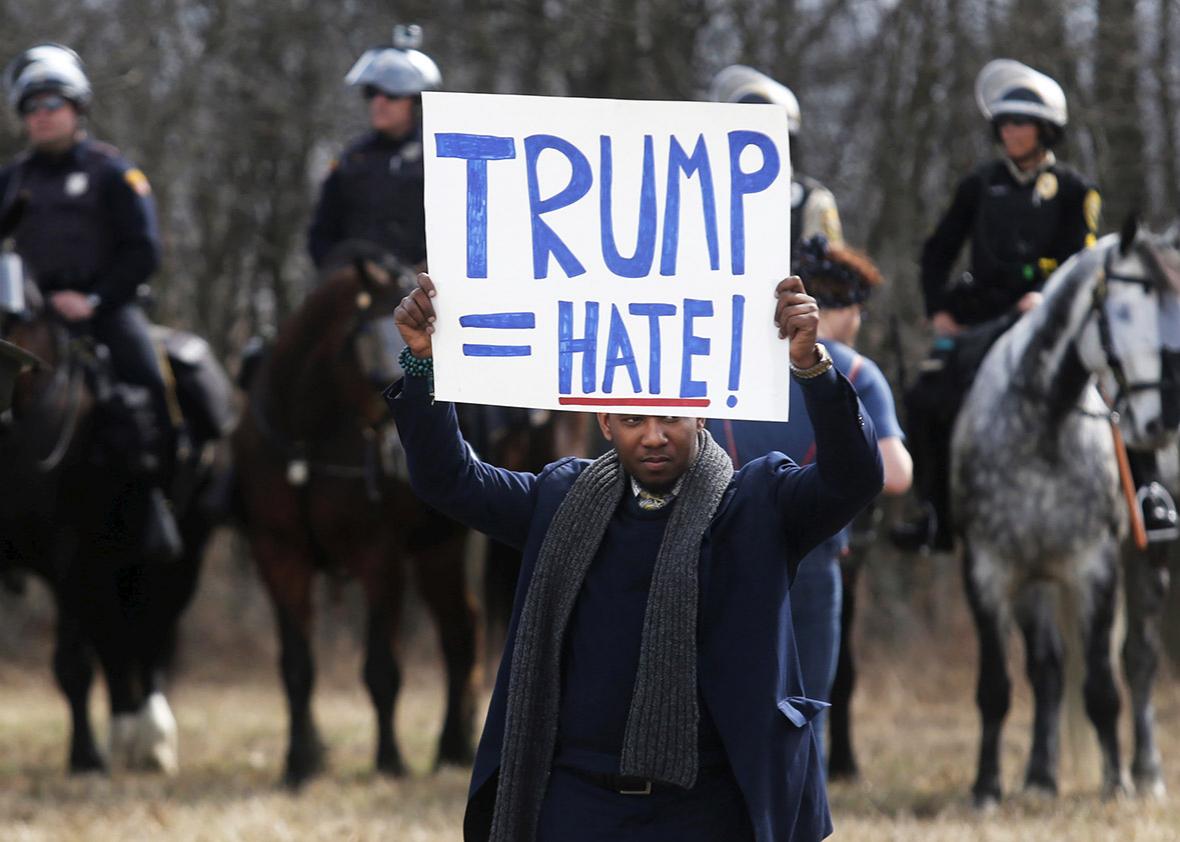 An anti-Trump protester holds his protest sign in front of mounted police outside a rally for Republican U.S. presidential candidate Donald Trump in Cleveland, Ohio, U.S. March 12, 2016.  