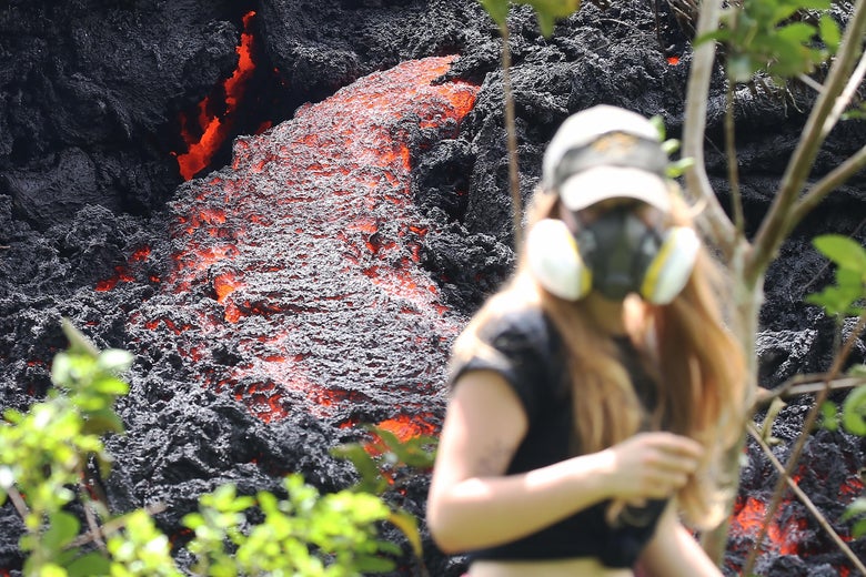 Lava flows at a new fissure in the aftermath of eruptions from the Kilauea volcano on Hawaii's Big Island as a local resident walks nearby after taking photos on May 12, 2018 in Pahoa, Hawaii.