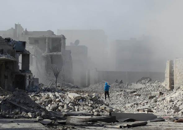 A Syrian man walks amid debris and dust following an alleged air strike by Syrian government forces on January 31, 2014 in the northern Syrian city of Aleppo.